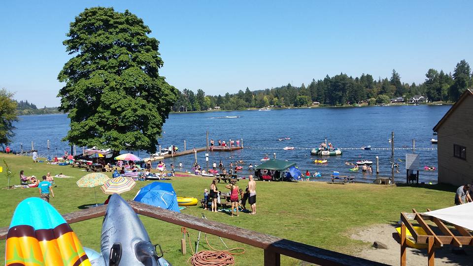 Visitors gather on the grassy bank and swim near the dock at Black Lake.